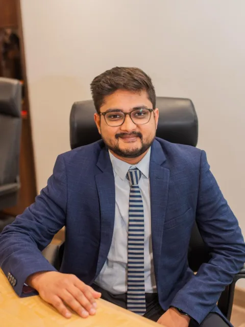 Portrait of the Chief Investment Officer, seated at his desk in a navy blazer and striped tie