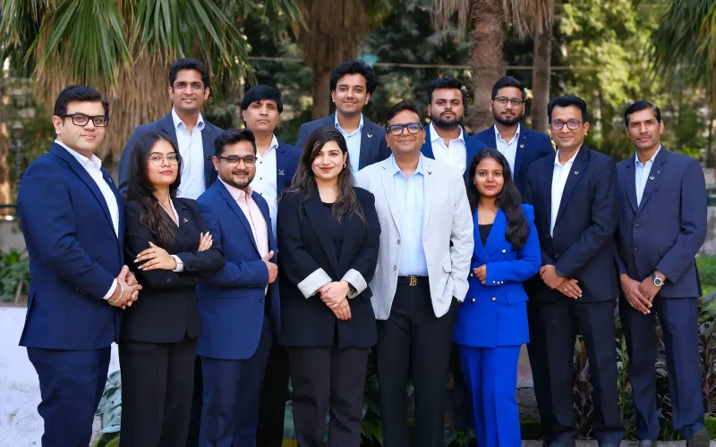 The iVentures Wealth team standing together outdoors in navy and black business attire, with palm trees behind