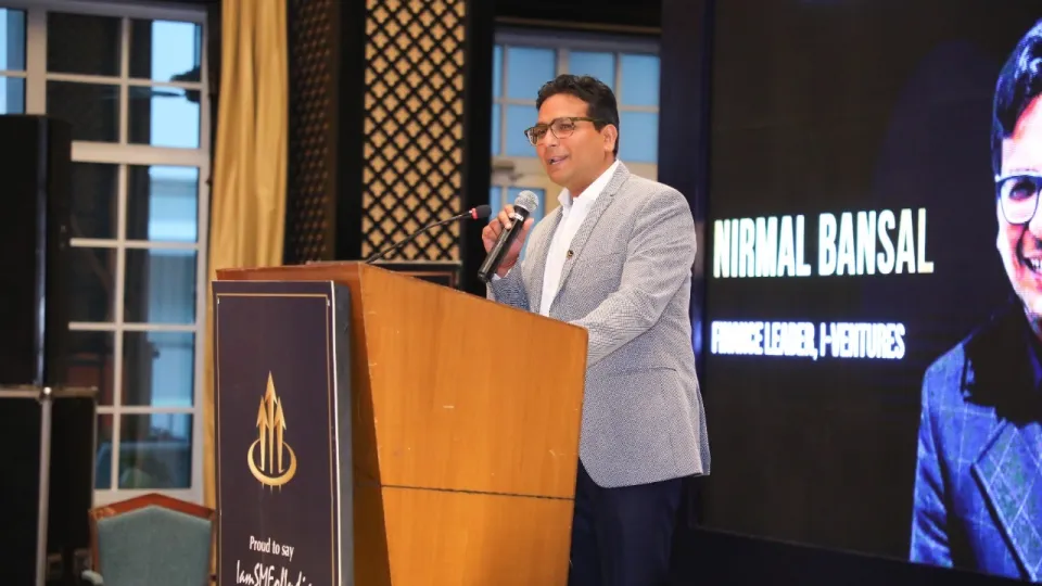 An iVentures speaker addressing an audience from a wooden podium at a finance conference